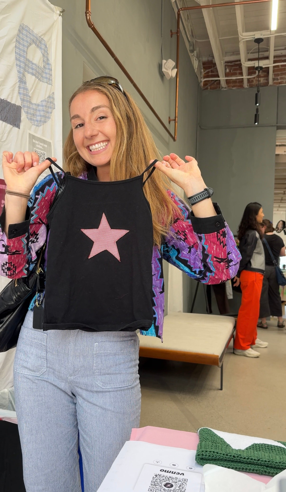 Maker holding up an upcycled black tank with a pink gingham star